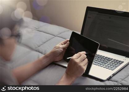 young designer working with digital tablet and stylus and computer in bed as concept