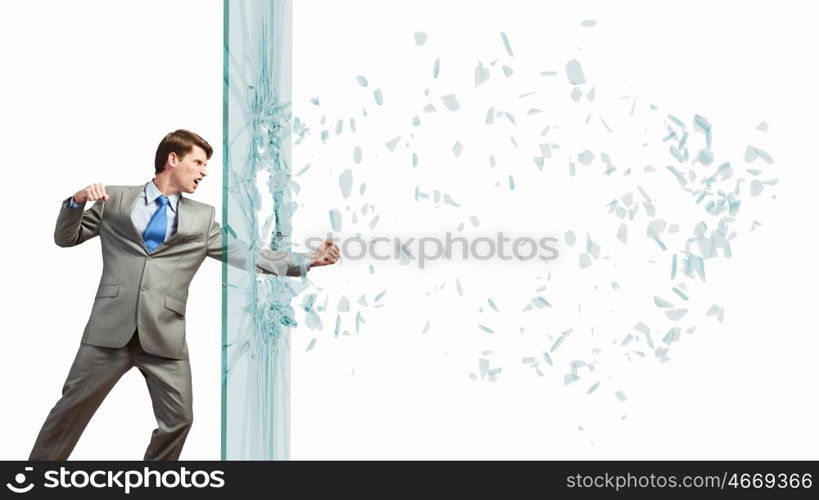 Young determined businessman breaking glass with karate punch. Businessman in anger