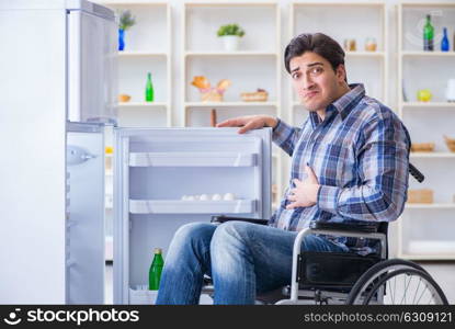 Young disabled injured man opening the fridge door