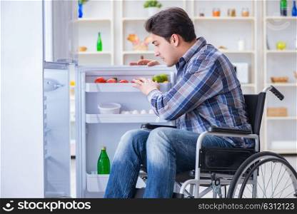 Young disabled injured man opening the fridge door . The young disabled injured man opening the fridge door