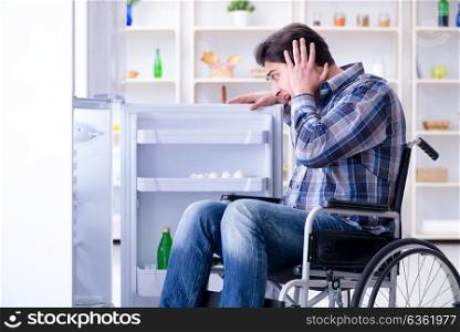 Young disabled injured man opening the fridge door