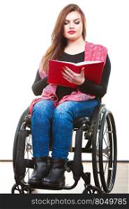 Young disabled woman in wheelchair with book.. Studying and reading concept. Disabilty and handicap. Young disabled woman on wheelchair reads book.