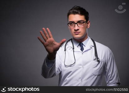 Young doctor against dark background