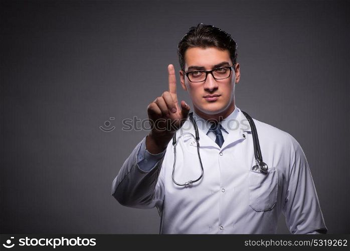 Young doctor against dark background