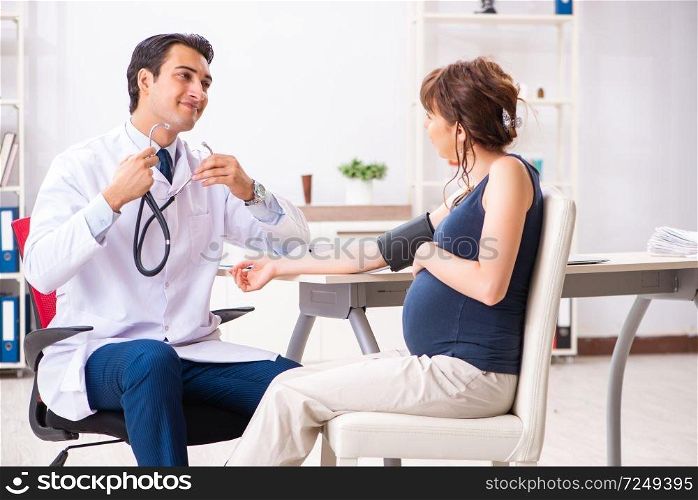 Young doctor checking pregnant woman&rsquo;s blood pressure