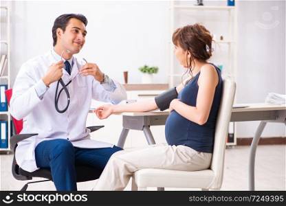 Young doctor checking pregnant woman&rsquo;s blood pressure