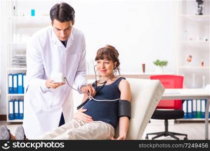 Young doctor checking pregnant woman’s blood pressure