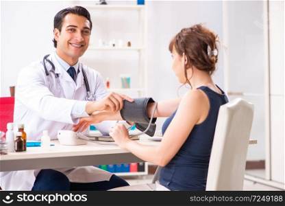 Young doctor checking woman&rsquo;s blood pressure