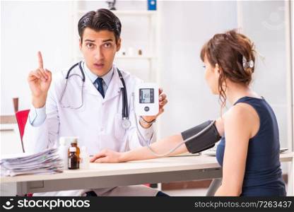 Young doctor checking woman&rsquo;s blood pressure. The young doctor checking woman&rsquo;s blood pressure