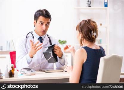 Young doctor checking woman’s blood pressure