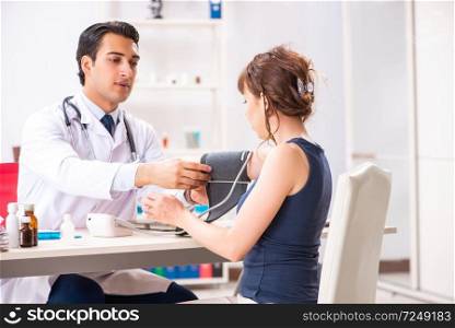 Young doctor checking woman’s blood pressure