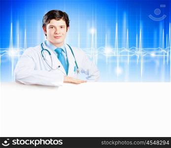 Young doctor. Image of handsome doctor holding white blank banner