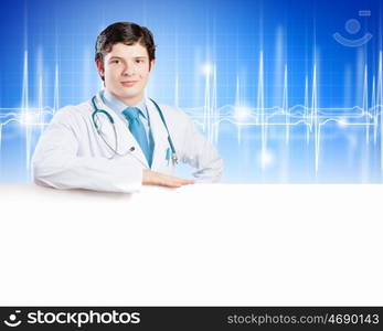 Young doctor. Image of handsome doctor holding white blank banner