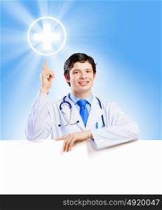 Young doctor. Image of handsome doctor holding white blank banner