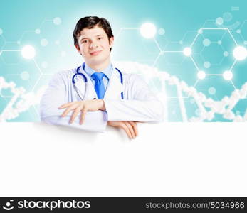 Young doctor. Image of handsome doctor holding white blank banner