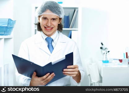 Young doctor in white uniform standing and holding papers