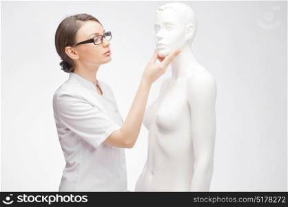 Young doctor observes a human mannequin on isolated background