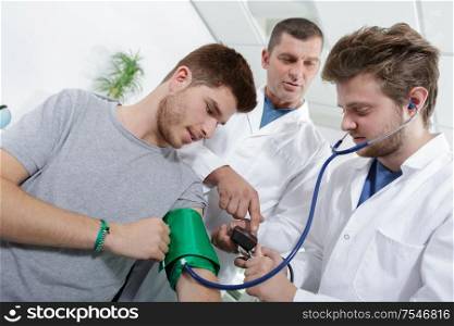 young doctor or nurse measuring patients pressure