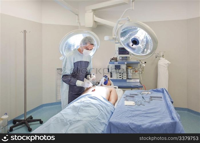 Young doctor performing operation on patient in operating room