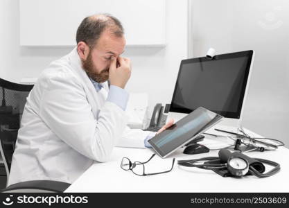 Young doctor rubbing his eyes, feeling tired and unhappy. Health care worker stress and frustration concept. High quality photography. Young doctor rubbing his eyes, feeling tired and unhappy. Health care worker stress and frustration concept