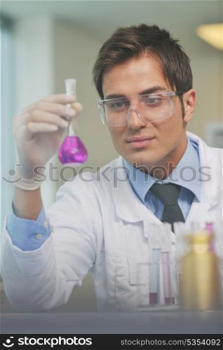 young doctor scientist in bright labaratory work research and analyse content of test tubes representing chemistry and research concept