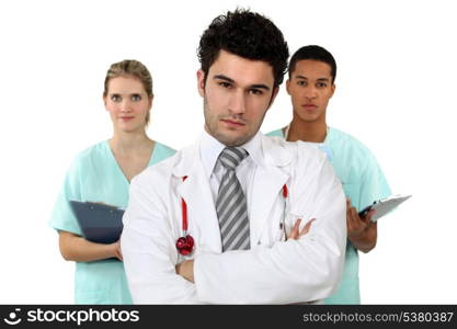young doctor standing cross-armed with male and female nurses in background