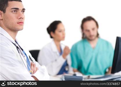 Young doctor thinking deeply, collegues discussing behind with computer in hospital