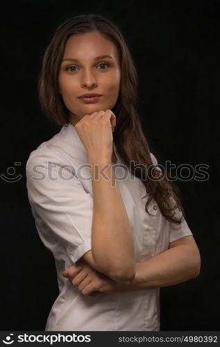 Young doctor wearing white coat thinking on black background