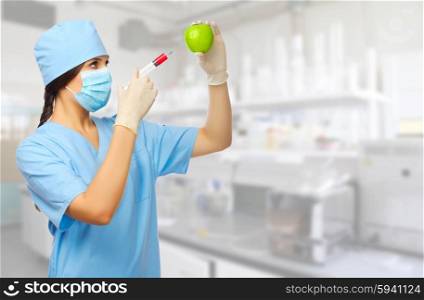 Young doctor with syringe and apple at laboratory
