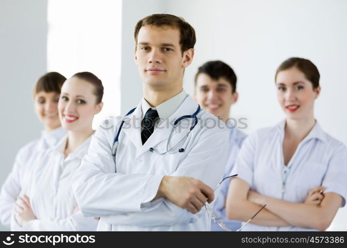 Young doctor. Young doctor in uniform and colleagues at background