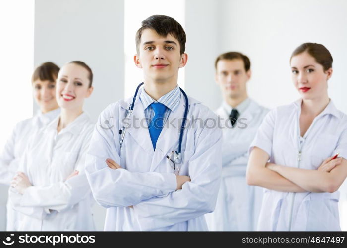 Young doctor. Young doctor in uniform and colleagues at background