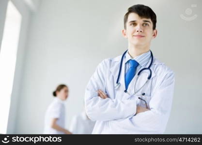 Young doctor. Young doctor in uniform and colleagues at background