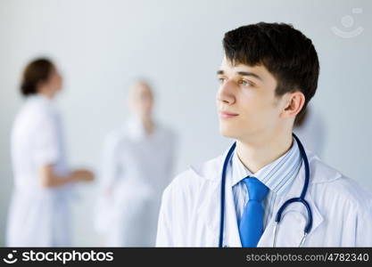 Young doctor. Young doctor in uniform and colleagues at background