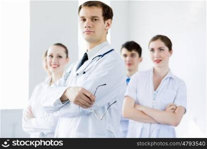 Young doctor. Young doctor in uniform and colleagues at background