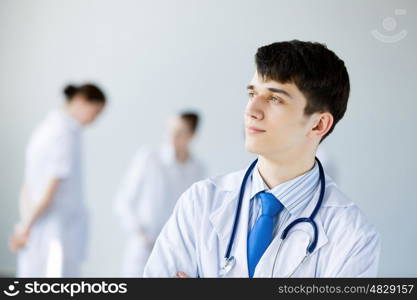 Young doctor. Young doctor in uniform and colleagues at background