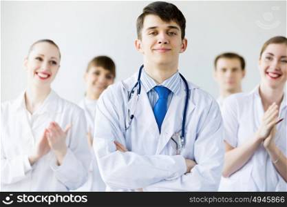 Young doctor. Young doctor in uniform and colleagues at background