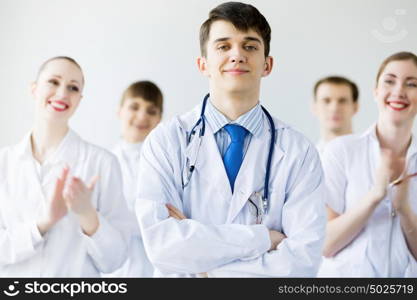 Young doctor. Young doctor in uniform and colleagues at background