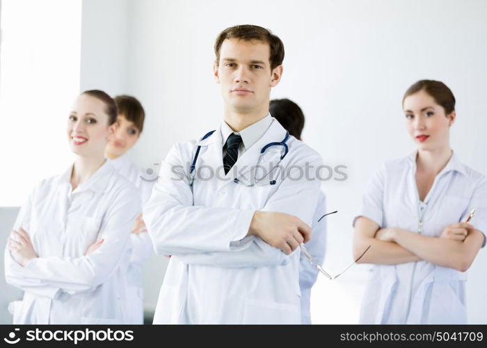 Young doctor. Young doctor in uniform and colleagues at background