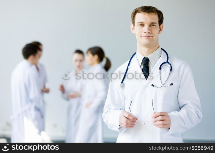 Young doctor. Young doctor in uniform and colleagues at background