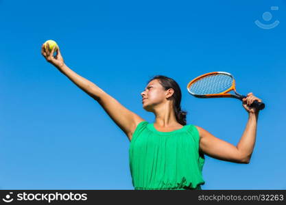 Young dutch woman with tennis racket and ball against blue sky