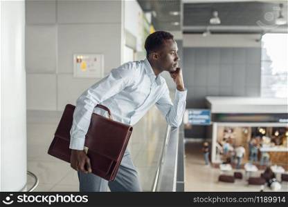 Young ebony businessman with briefcase looking on food-court. Successful business person in cafe, black man in formal wear