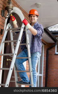 Young electrician in hardhat climbing the stepladder