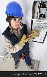 Young electrician stood by fuse box