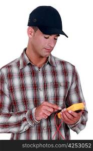 young electrician wearing cap using tester