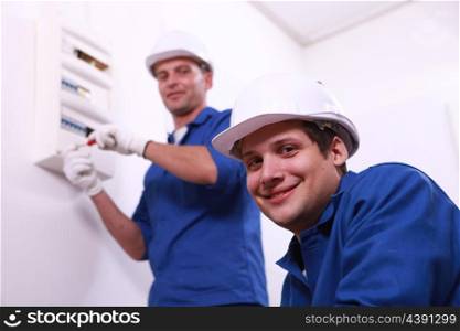 Young electricians with a fusebox