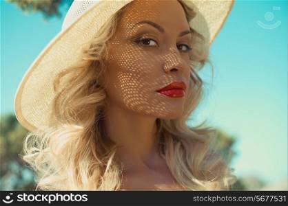 Young elegant lady in the sunlight through the hat