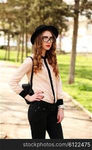 Young elegant woman in stylish clothes. Model with red lips in hipster cloth and vintage black hat in sunglasses. Fashion shot. Modern youth lifestyle concept.