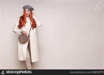 Young elegant woman in trendy white coat. Blond hair, gray beret, isolated studio shot. Fashion autumn lookbook. Model woman with dyed hair