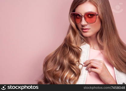 Young elegant woman in trendy white coat. Blond hair, pink dress, isolated studio shot. Fashion autumn lookbook. Model woman in sunglasses