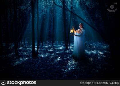 Young elven girl with lantern at night forest
